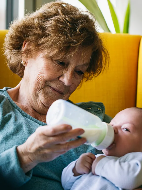 A grandmother feeding her newborn grandchild